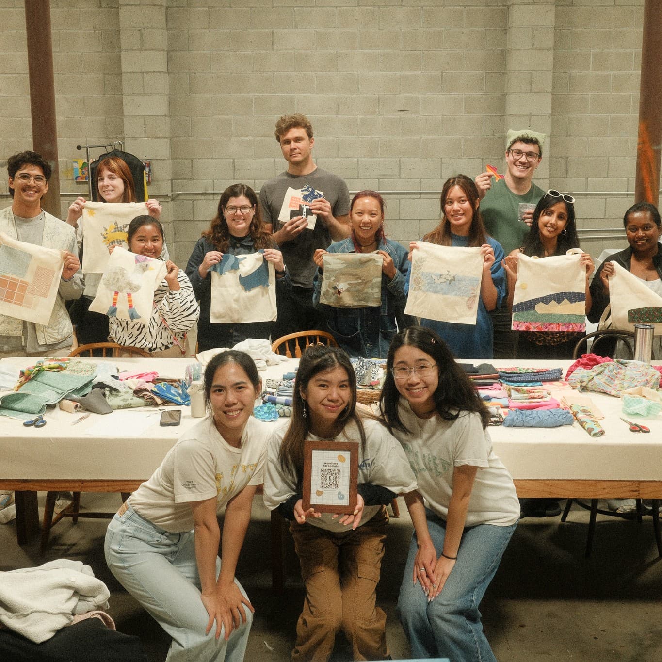 A group of GLUED community club members holding up their handmade tote bags
